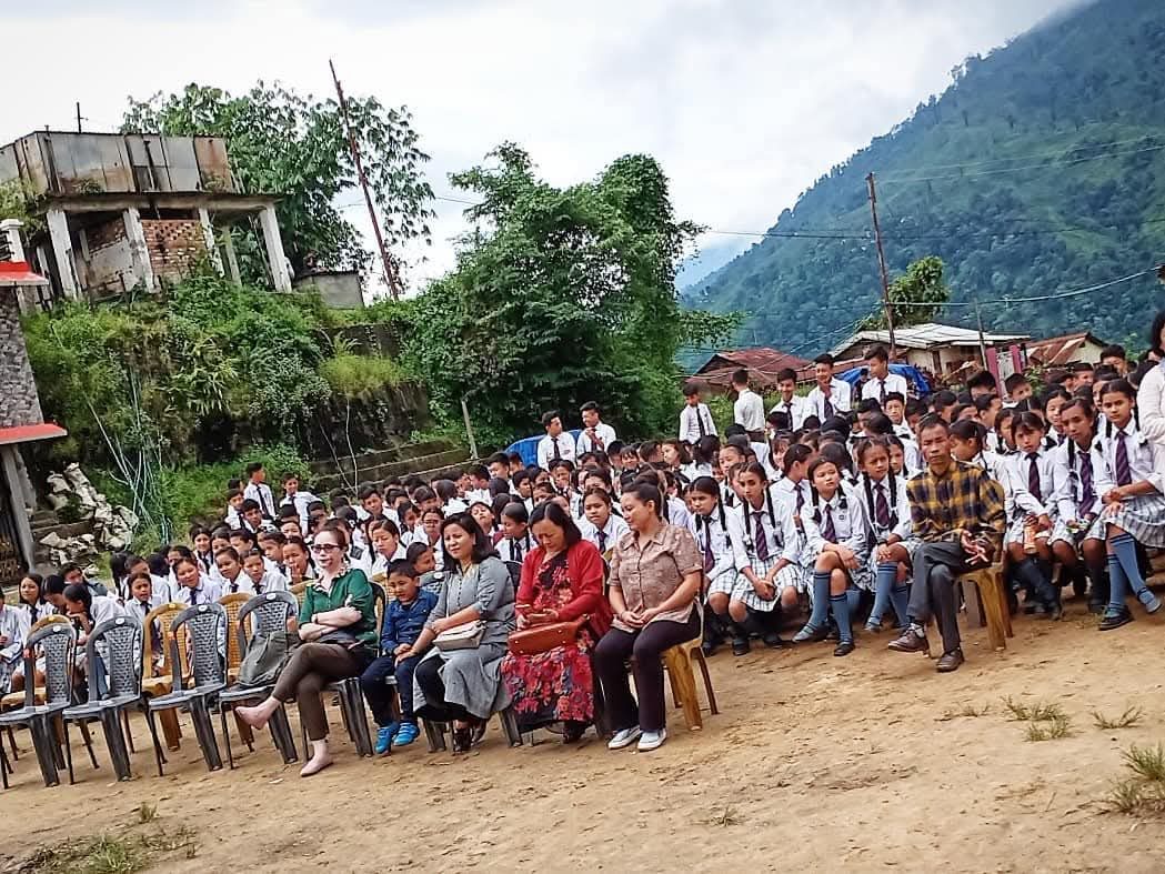 A large gathering of students and community members on a hillside
