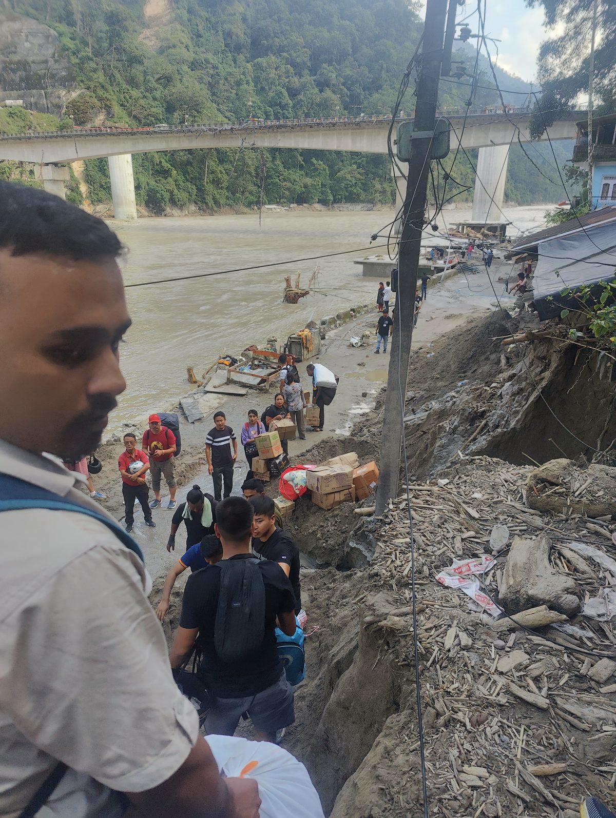 Volunteers walking beside the swollen Teesta river